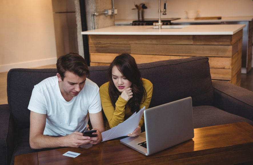 Couple reviewing internet and streaming bundles with a laptop and bill at home.