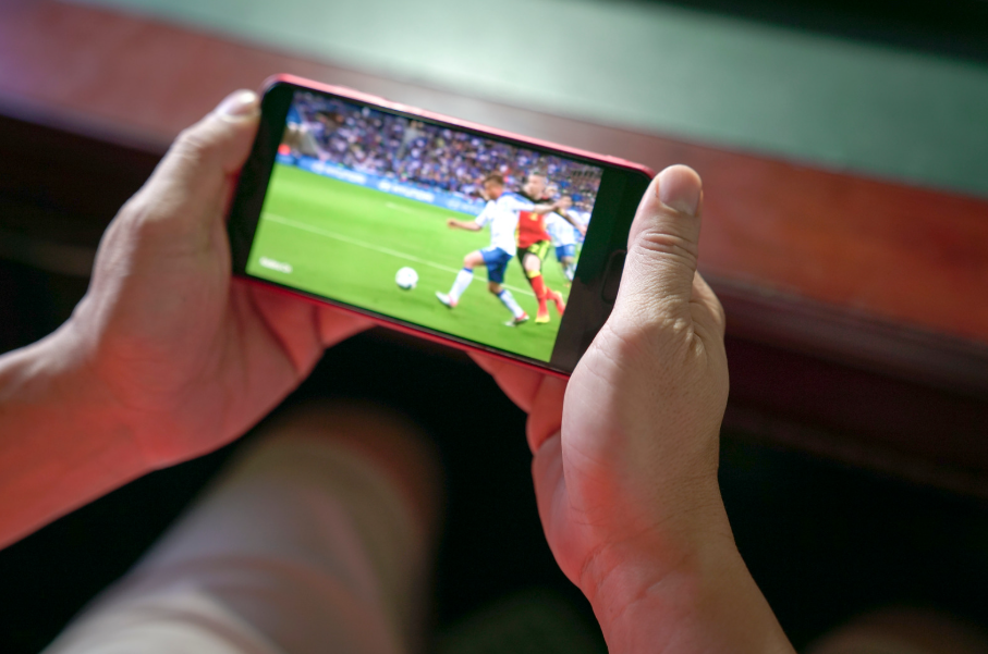 Hands holding a phone to watch live sports without cable.